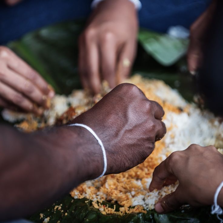 Hands eating from a banana leaf
